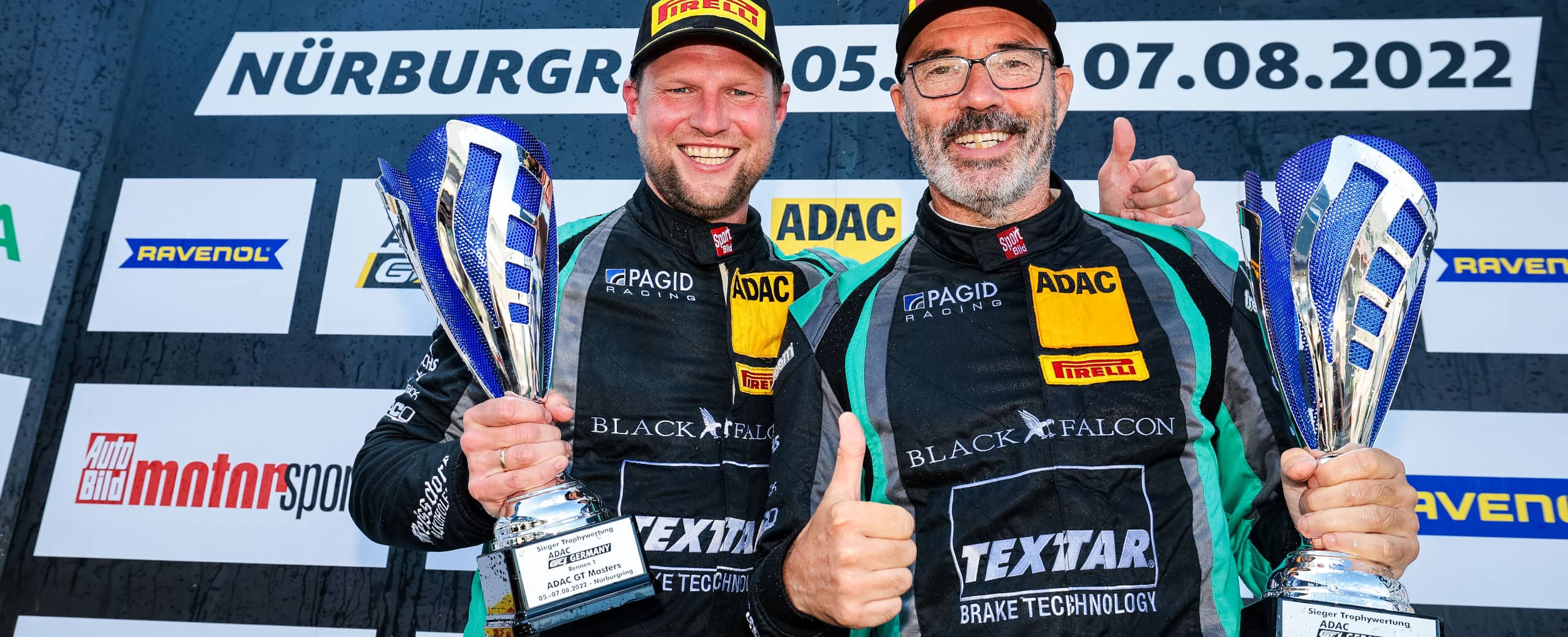 Daniel Schwerfeld und Axel Sartingen als Sieger mit Pokal auf dem Podium der ADAC GT4 Germany auf dem Nürburgring 2022, BLACK FALCON Team TEXTAR